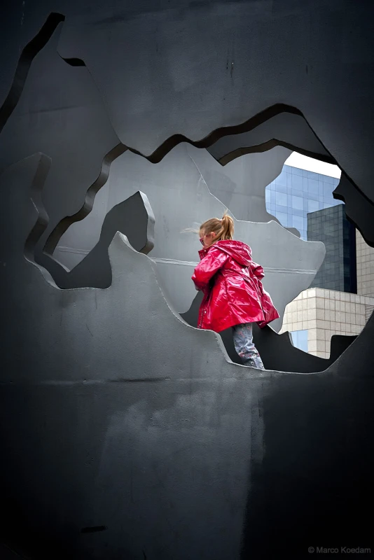Meisje in rode regenjas in coulissen van architectuur en kunstwerk. Centrum, Barcelona