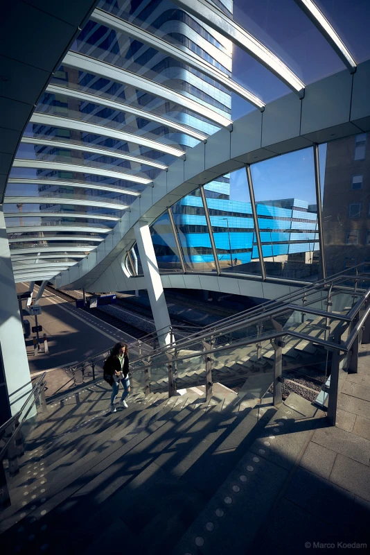 Vrouw loopt trap op in het station van Arnhem omringt door complexe architectuur. Centrum, Arnhem